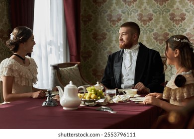 Portrait of classic gentleman enjoying tea with two young ladies sitting at table together in classic ornate room, copy space - Powered by Shutterstock