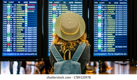 portrait and close up of the back of curly woman checking the time of her flight in the airport to traveling outdoors and enjoy her vacations - noamd lifestyle and concept - Shutterstock ID 1789133978
