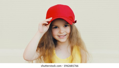 Portrait close up beautiful little girl kid with long hair wearing a red baseball cap