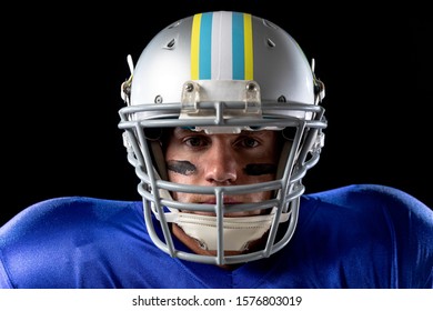 Portrait Close Up Of A Caucasian Male American Football Player Wearing A Team Uniform, Pads And A Helmet. With Eye Black Under His Eyes.