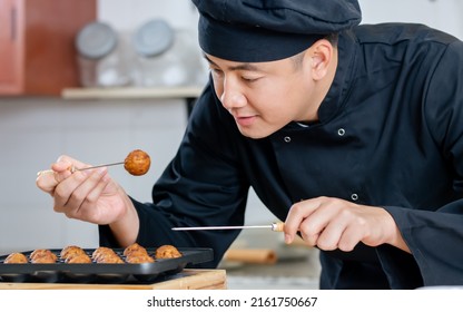 Portrait Close Up Handsome Professional Japanese Male Chef Wearing Black Uniform, Hat, Cooking, Making Takoyaki Street Food, Smiling With Confidence, Standing In Kitchen. Restaurant, Hotel Concept