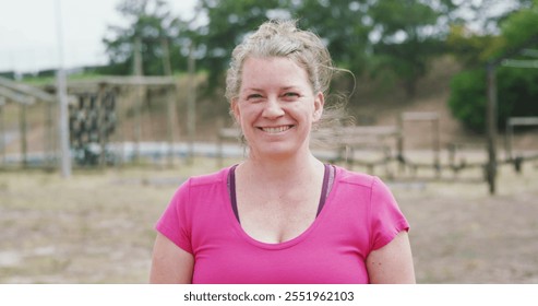 Portrait close up of a happy Caucasian woman standing at boot camp, looking to camera and smiling, wearing a pink t shirt, in slow motion - Powered by Shutterstock