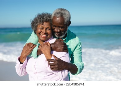 Portrait close up of a senior African American couple standing on the beach with blue sky and sea in the background, embracing and smiling  - Powered by Shutterstock