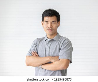 Portrait Close Up Shot Of Handsome Asian Male Model With Short Black Hair Wearing Gray Polo Shirt Stand Smiling In Front Of White Background.