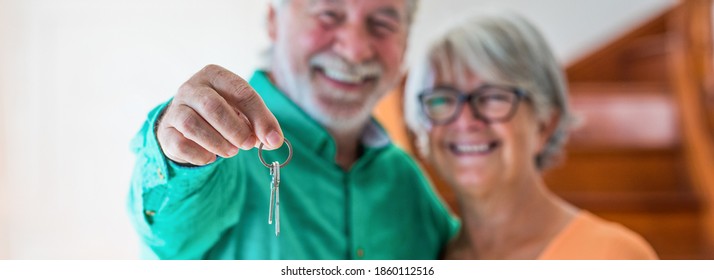 portrait and close up of two happy seniors buying a new house holding the key with his hand