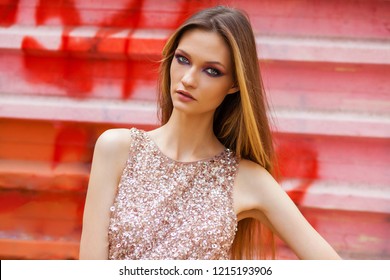 Portrait close up of young beautiful blonde woman in pink dress, summer street