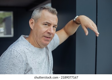 Portrait Closeup Of Attractive Aged Gray Haired Man Leaning Arm On Gray Construction Of Modern Office Building, Selective Focus. Urban Lifestyle, Stylish Architecture, Business Center, Relaxation.