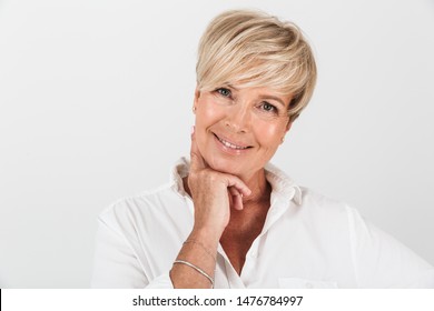 Portrait, Nahaufnahme einer schönen erwachsenen Frau mit kurzen blonden Haaren, die bei der Kamera lächeln, einzeln auf weißem Hintergrund im Studio