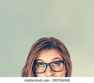 Portrait closeup funny confused skeptical woman girl female face with glasses looking up isolated green wall background copy space above head. Human expressions, emotions, feelings, body language - Shutterstock ID 1907036968