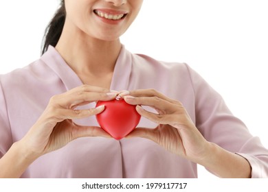 Portrait Closeup Isolated Cut Out Shot Of Asian Young Happy Hospital Blood Donor Patient Hold Red Rubber Heart In Hands On Chest In Front White Background With Copy Space For Insurance Advertisement.