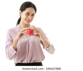 Portrait Closeup Isolated Cut Out Shot Of Asian Young Happy Hospital Blood Donor Patient Hold Red Rubber Heart In Hands On Chest In Front White Background With Copy Space For Insurance Advertisement.