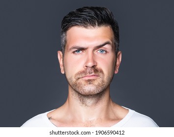 Portrait closeup of one handsome sensual shaved man with bristle and eyebrow raised model looking forward in studio on grey background, vertical picture