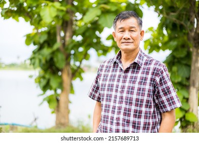 Portrait Close-up Shot Of Middle-aged Asian Male Model With Short Black Hair Wearing A Plaid Shirt With Stand Smiling In The Park