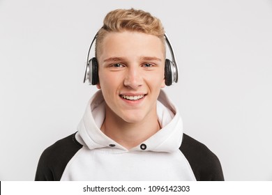 Portrait Closeup Of Teenage Boy 16-18 Years Old Wearing Hoodie And Wireless Headphones Posing With Happy Smile Isolated Over White Background