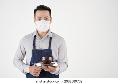 Portrait Of Coffeeshop Waiter In Medical Mask Serving Cup Of Freshly Made Coffee