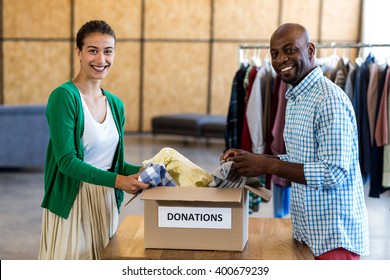 Portrait of colleagues sorting clothes from donation box in the office - Powered by Shutterstock