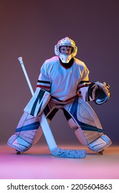 Portrait Of Concentrated Boy, Child, Goalkeeper, Training Hockey Game Isolated Over Purple Background In Neon Light. Concept Of Sportive Lifestyle, Childhood, Hobby, Action. Copy Space For Ad