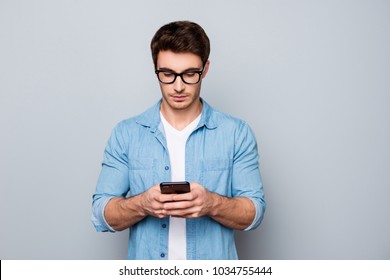 Portrait of concentrated, busy, trendy, modern, brunet guy with stubble, hairstyle having smart phone in hands, checking email, using 3G, wi-fi internet, searching contact, isolated on grey background - Powered by Shutterstock