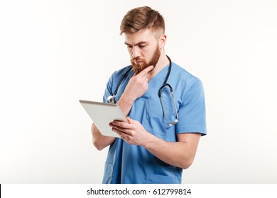 Portrait Of A Concentrated Pensive Medical Doctor Or Nurse Thinking While Looking At Tablet Computer Isolated On White Background