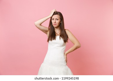 Portrait of concerned puzzled bride woman in white wedding dress stand have problem keeping hand on head isolated on pink pastel background. Wedding celebration concept. Copy space for advertisement - Powered by Shutterstock