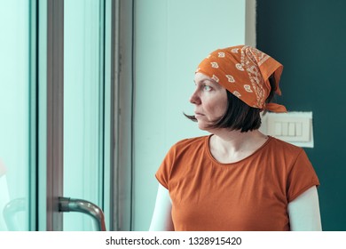 Portrait Of Concerned Self Employed Female Carpenter Looking Out Through The Window Of Her Small Business Woodwork Workshop