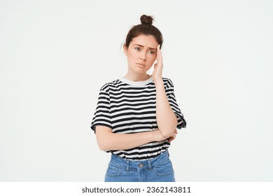 Portrait of concerned, worried young woman, touches her head, looking complicated, standing over white background. - Powered by Shutterstock