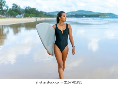 Portrait of Confidence Asian woman in swimwear holding surfboard and walking on tropical beach at summer sunset. Happy female enjoy outdoor activity lifestyle extreme sports surfing on summer vacation - Powered by Shutterstock