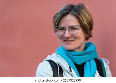 Portrait Of A Confident 35 Year Old White Woman With A Salmon Pink Colored Background