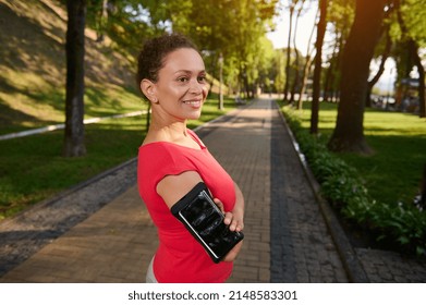 Portrait Of A Confident 40 Years Old African American Woman In Sportswear Standing In Forest City Park With Her Arms Crossed And Smiling With A Beautiful Toothy Smile During Her Morning Run Or Workout