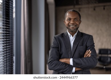 Portrait of a confident African American businessman with a warm smile standing in a modern office setting. - Powered by Shutterstock