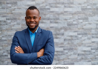 Portrait of confident african american male professional wearing blue suit using smartphone while standing against brick wall outside office - Powered by Shutterstock