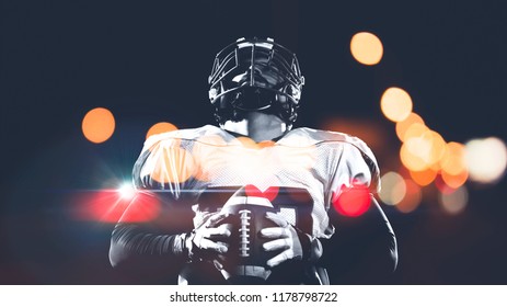 portrait of confident American football player holding ball while standing on field at night