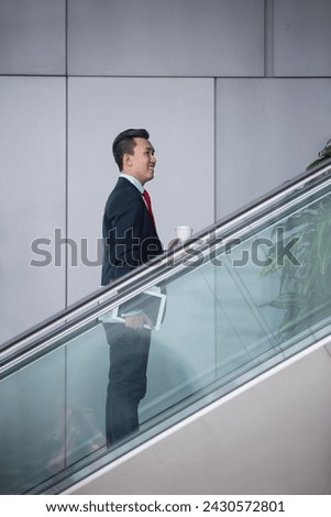 Portrait of a confident asian businessman standing on an escalator in the city.