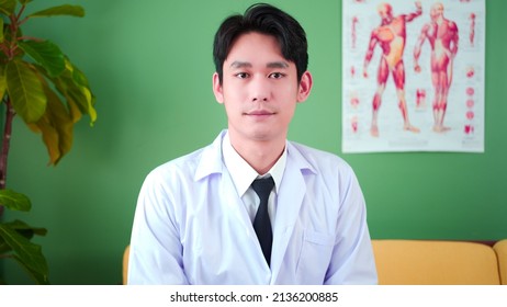 Portrait Of Confident Asian Young Male Physician Posing In Hospital Medical Office. Expertise, Professional Doctor In Uniform White Lab Coat With Arms Crossed.