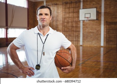 Portrait Of Confident Basketball Coach Holding Ball While Standing In Court