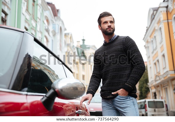 Portrait of a confident bearded man in sweater\
getting into his car\
outdoors