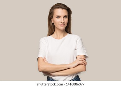 Portrait Of Confident Beautiful Young Woman With Arms Crossed, Attractive Female Wearing White T-shirt Looking At Camera, Successful Businesswoman Posing Isolated On Grey Studio Background