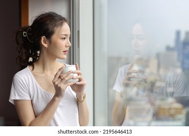 Portrait Of Confident And Beauty Young Asian Businesswoman With Coffee Cup Standing And Looking Away In Modern Hotel With City Blurred Background. Success Business And Lifestyle Concept