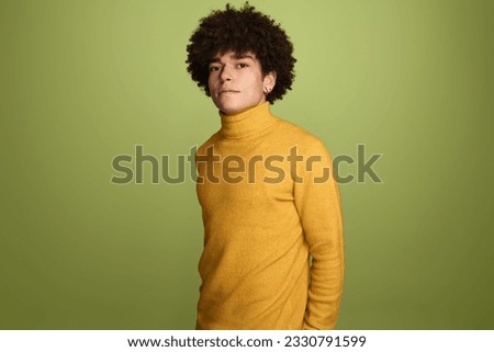 Portrait of confident Brazilian male fashion model with dark curly hairstyle in casual wear gazing at camera against green background Stock photo © 
