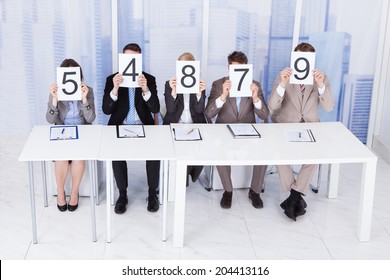 Portrait Of Confident Business People Showing Score Cards