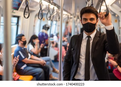 Portrait of confident businessman in black suit wear mask in city finding job during corona crisis using smartphone travelling on empty train - Shutterstock ID 1740400223