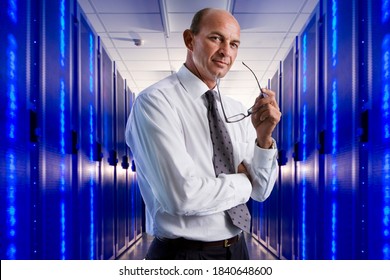 Portrait Of A Confident Businessman Holding Eyeglasses Standing In The Middle Of A Large Data Center Server Room