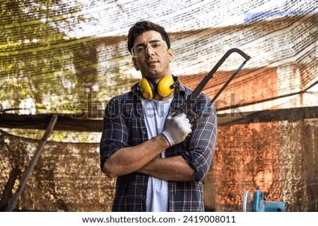 Portrait confident Caucasian carpenter man holding manual hand saw in local vintage carpenter work place