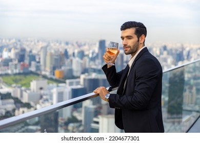 Portrait of Confident Caucasian man enjoy outdoor lifestyle drinking wine while celebrating holiday dinner party at skyscraper rooftop restaurant and bar with looking to city skyline at summer sunset. - Powered by Shutterstock