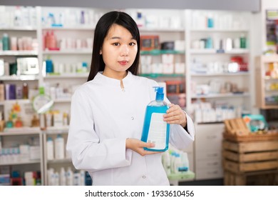 Portrait of confident chinese female pharmacist is standing with medicines in pharmacy