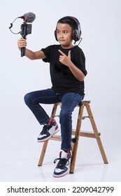 Portrait Of Confident And Creative Asian Child Blogger Talking On Camera In A Studio. Online Influencer Vlogger Children Boy Social Media Live Streaming Concept.