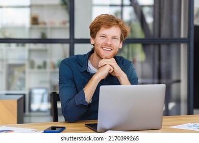 Portrait Of Confident Entrepreneur Or Small Business Owner In A Modern Office Or Coworking Space Successful Young Businessman Is Working Using Laptop Sitting Workplace Looking At The Camera And Smile