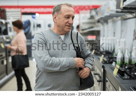 Portrait of a confident European man of mature age, who came to the electronics and household appliances store for a ..purchase, in the gas stoves department