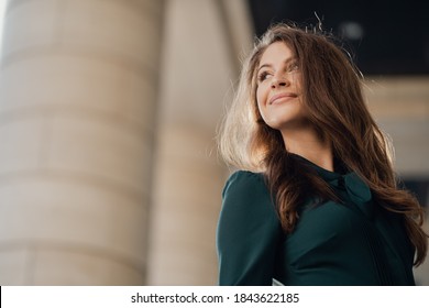 Portrait Of Confident Eye, Strong Nature Poses Of A Happy Young Female Student Caucasian Appearance Brunette In A Green Dress, Turns Around Looking To The Side