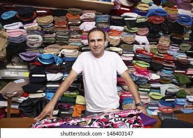 Portrait of confident fabric store owner standing at counter